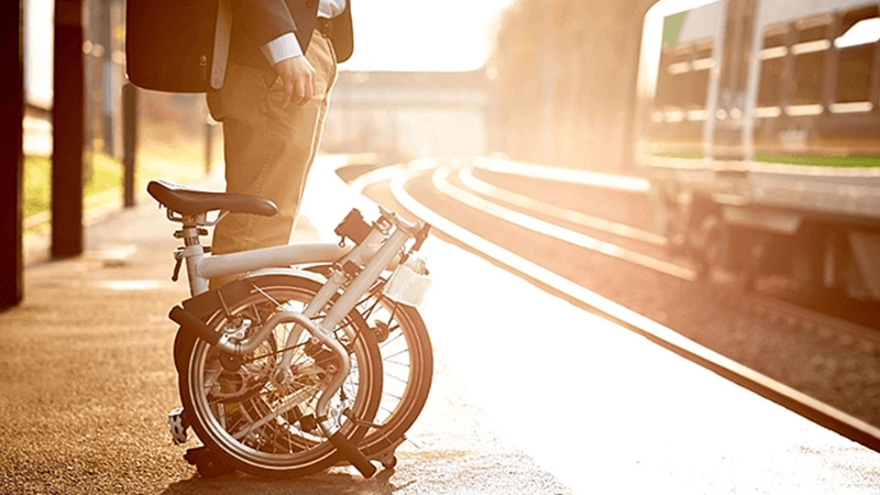 Ein Businessmensch mit Faltrad wartet auf den Zug