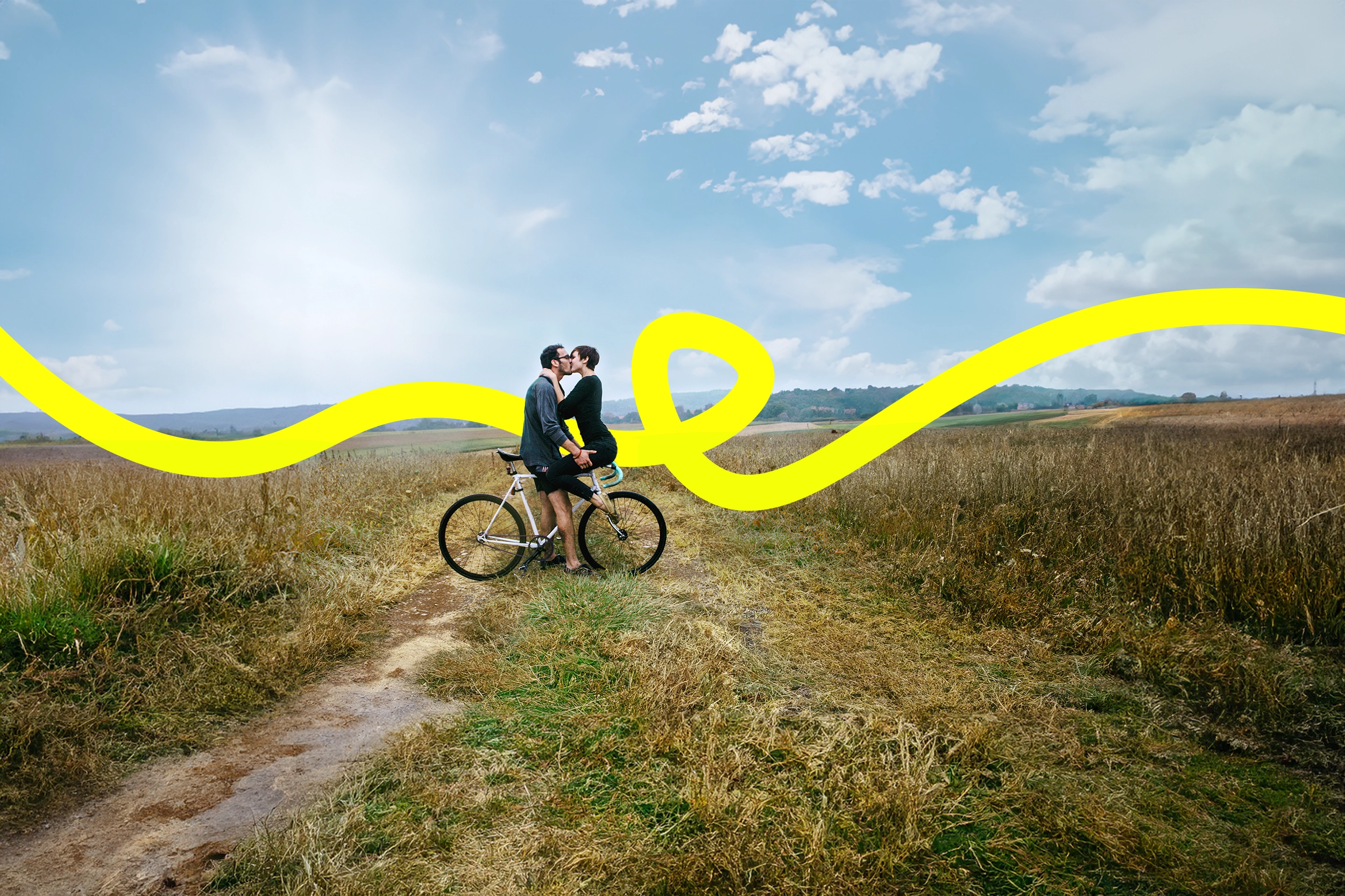 Ein Heteropärchen küsst auf dem Fahrrad auf dem Feldweg, die JobRad Loop Linie kringelt sich durchs Bild